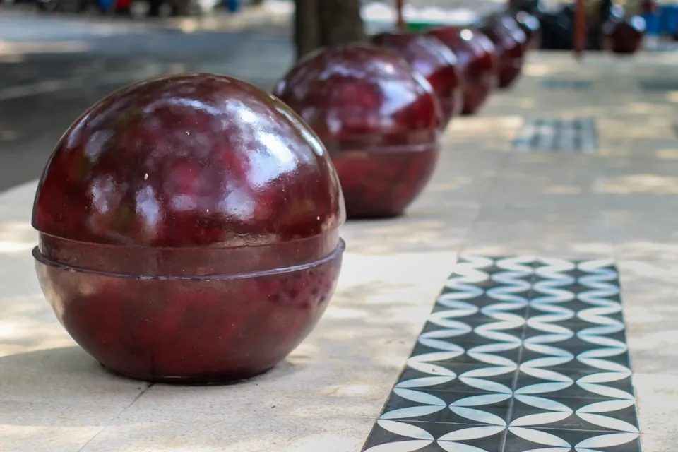 Red spherical bollards lining city sidewalk.
